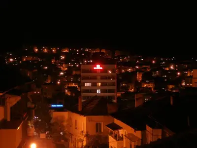 a city at night with a red light on top of a building at Apartments in House Silent Nature in Sandanski