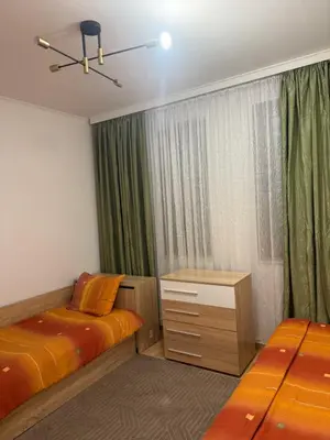 a bedroom with two beds and a window with green curtains at Пампорово , Манастира 3 in Pamporovo