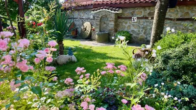a garden with pink flowers and a stone building at Iliikova House in Kalofer