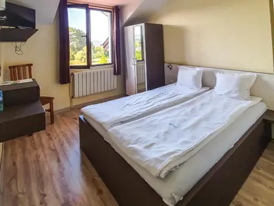 a large bed with white sheets in a bedroom at Dolna Bania Hotel in Dolna Banya