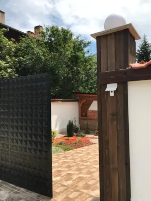 a gate to a garden with a bird house at КЪЩА ЗА ГОСТИ ХАРМОНИ in Shiroki Dol