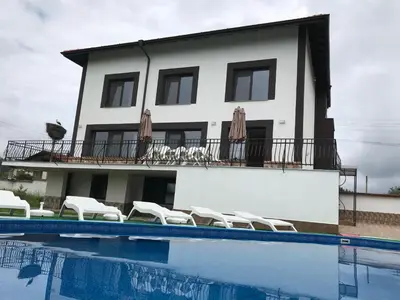 a house with a swimming pool in front of a building at КЪЩА ЗА ГОСТИ ХАРМОНИ in Shiroki Dol