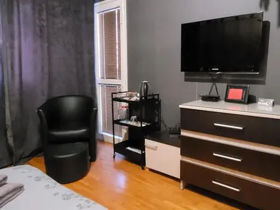 a bedroom with a dresser with a television and a chair at New York - Room for overnight travelers near the Airport, parking in Sofia