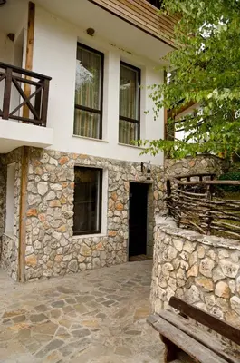 a building with a stone wall and a bench at Boriki Complex in Pamporovo