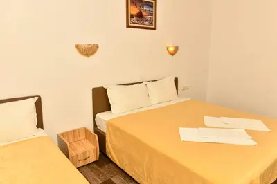 a small room with two beds with yellow sheets at Blyan Family Hotel in Chiflik