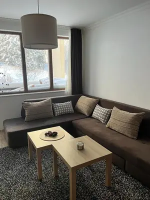 a living room with a brown couch and a coffee table at Ski 'Inn Monastery 3 Ski-to-Door in Pamporovo