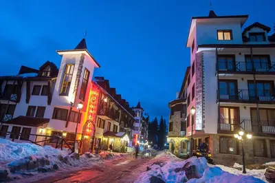 a city street with buildings in the snow at night at Pamporovo Apartment 314 The Castle 3 in Pamporovo