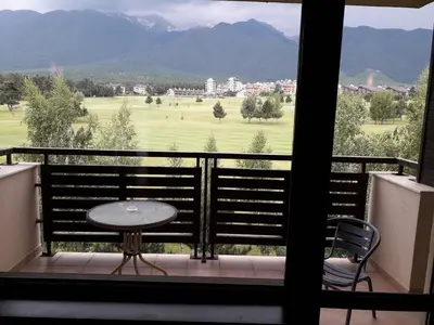 a balcony with a table and a view of a golf course at Terra Complex SPA apartment 1 bedroom suite in Razlog