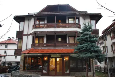 a building with a tree in front of it at Guest House ANEX in Bansko