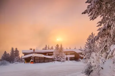 a lodge in the snow with the sun setting in the background at Hotel and Relax Moreni in Sofia