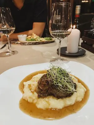 a plate of food on a table with wine glasses at Hotel and Relax Moreni in Sofia