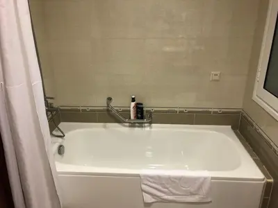a white bath tub with a towel and a mirror at Mountain View Apartment in Bansko