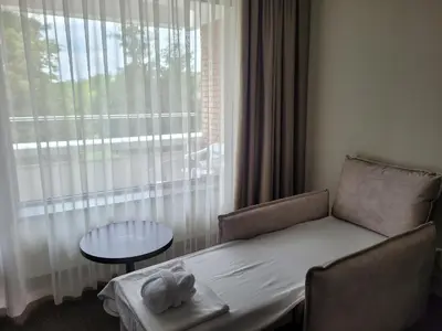 a bed in a room with a window and a table at Sana Spa Hotel in Hisarya