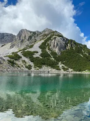 a mountain reflecting in the water of a lake at TM HOUSE - Private Rooms in Bansko
