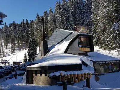 a snow covered building with a snow covered roof at Апартамент Pamporovo Palace in Pamporovo
