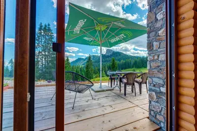 a patio with a table and chairs and an umbrella at Вила Морава in Pamporovo