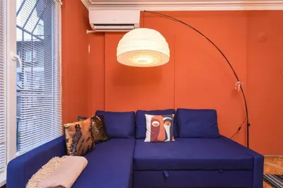 a blue couch in a room with an orange wall at Vintage Spot - Colorful One-Bedroom Apartment by Flat Mаnager in Sofia