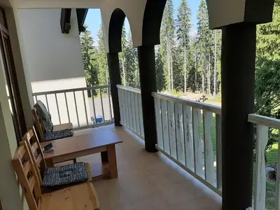 a balcony of a house with a table and chairs at Апартамент КАРЛИН in Pamporovo
