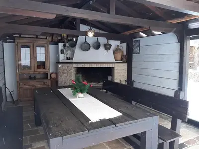 a kitchen with a wooden table and a fireplace at Апартамент КАРЛИН in Pamporovo