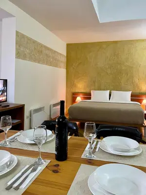 a dining table with plates and wine glasses on it at Dolomiti Apartments in Bansko