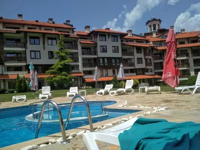 a hotel with a swimming pool in front of a building at Sunny studio apartment - few steps from Gondola in Bansko