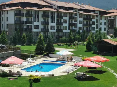 a large hotel with a swimming pool and umbrellas at Sunny studio apartment - few steps from Gondola in Bansko