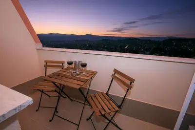 a table and two chairs on a balcony with wine glasses at ГеВе Апартаменти in Sandanski
