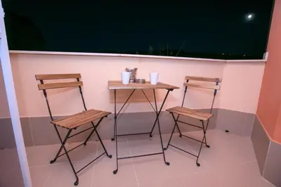 a small table and two stools in front of a wall at ГеВе Апартаменти in Sandanski