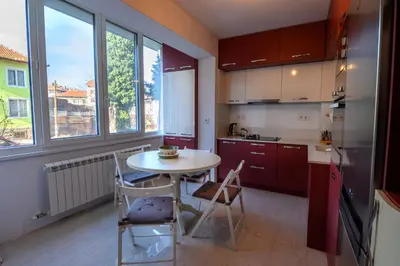 a kitchen with a table and chairs in a room at Апартамент за гости Римски терми in Kyustendil