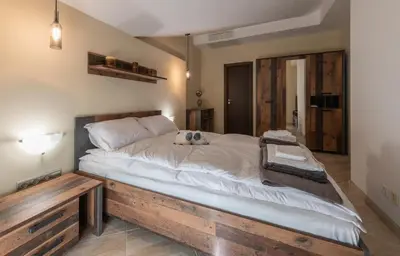 a large bed with a wooden frame in a room at Апартаменти Ковачева in Bansko