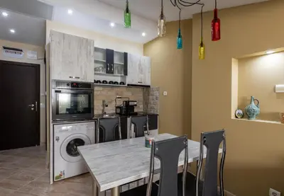 a kitchen with a table and a washing machine at Апартаменти Ковачева in Bansko