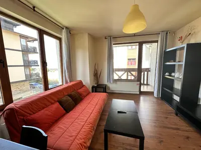 a living room with a red couch and a table at Neon Luxury apartments next to the Gondola in Bansko