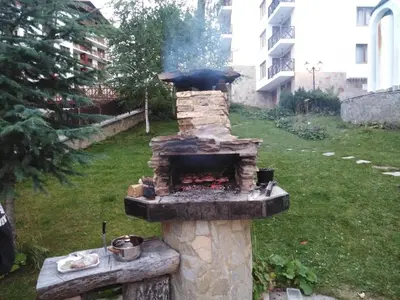 a stone fireplace with a grill in a yard at Studio at Home Pamporovo in Pamporovo