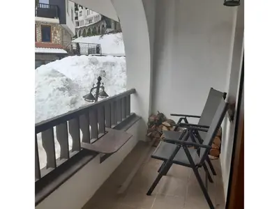 a room with a balcony with a chair and snow at Apartament Harmony in Monastery complex in Pamporovo