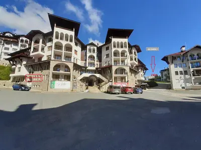 a large building with cars parked in front of it at Apartament Harmony in Monastery complex in Pamporovo