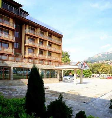 a hotel with a parking lot in front of a building at Olymp Hotel in Teteven