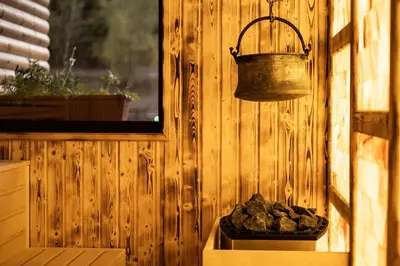 a bell hanging from a wooden wall with a box of rocks at Thermal Camping Velingrad in Velingrad
