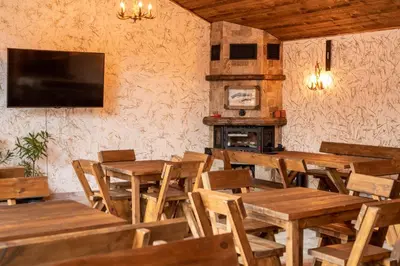 a restaurant with wooden tables and chairs and a fireplace at Thermal Camping Velingrad in Velingrad