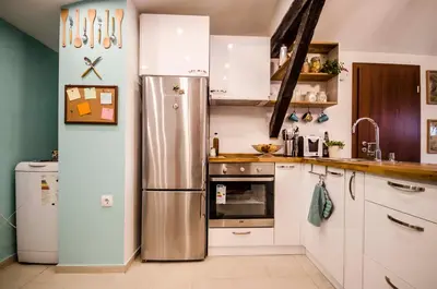 a kitchen with white cabinets and a stainless steel refrigerator at Off Vitosha Blvd Designer Apart in Sofia