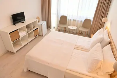 a white bedroom with a large bed and a television at Guest House 7 in Bansko