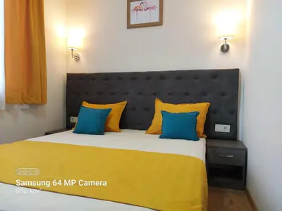 a bedroom with a large bed with yellow and blue pillows at Sharkov Family Hotel in Ognyanovo
