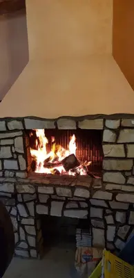 a stone fireplace with a fire in it at Къщи за гости Ореха in Samokov