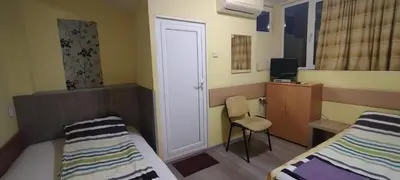 a room with two beds and a chair and a door at East Gate Guest Rooms in Plovdiv