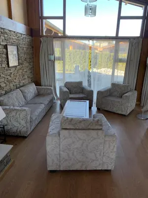 a living room with couches and a table and windows at House in Pirin Golf Bansko in Razlog