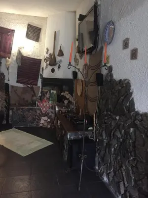 a living room with a fireplace and a table at Къща за гости Спасителна in Brezhani