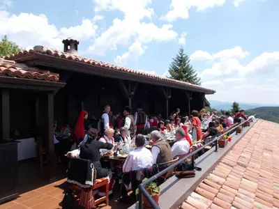 a group of people sitting at tables on a patio at Panorama Family Hotel in Zlatograd