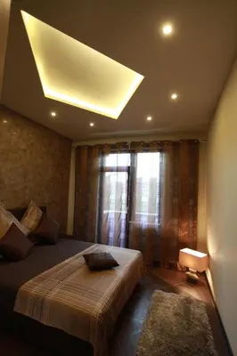 a bedroom with a large bed with a light on the ceiling at Brown Cottage Apartment in Sofia