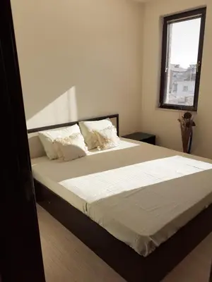 a bedroom with a bed with white sheets and a window at Apartament Emi in Sandanski
