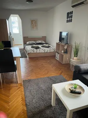 a living room with a bed and a table at Студио Рози апартамент in Sandanski