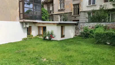 a house with a green yard in front of a building at Ancient Serdica 2BDR Family Friendly City Retreat in Sofia